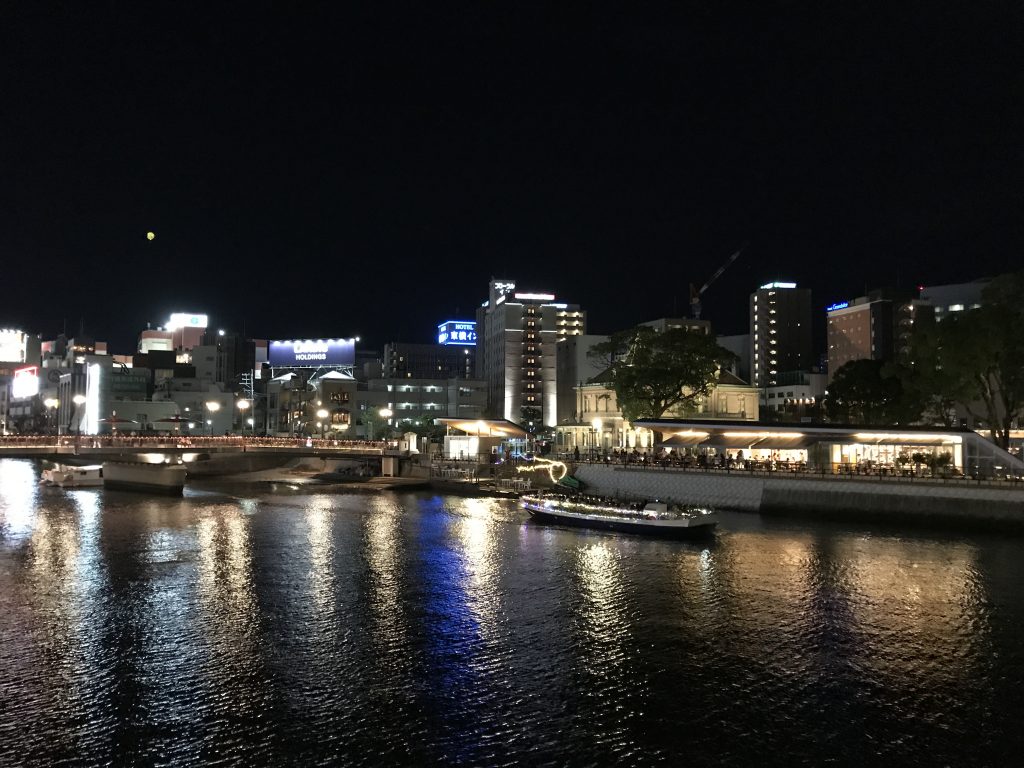 夜景が写る川面に浮かぶ水上バス。左手に見えるのが福博であい橋